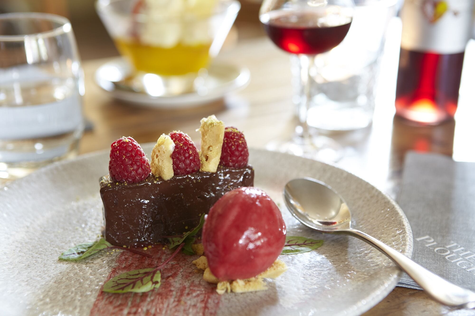 A dessert plate with chocolate cake, raspberries, and a scoop of ice cream.