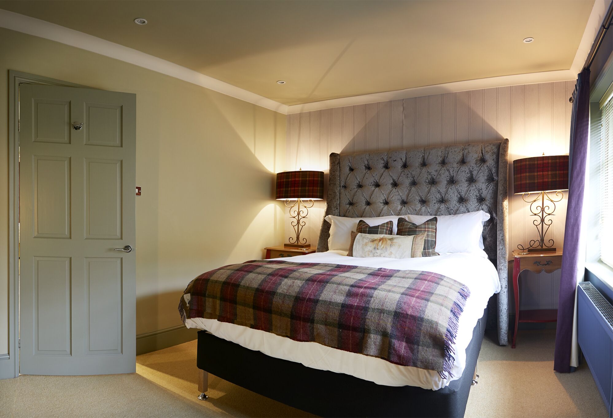 A bedroom with a large bed, two bedside tables, and a door.