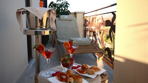 Varanda com mesa posta para o café da manhã, incluindo croissants, morangos e um copo de martini.