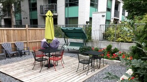 A patio with outdoor furniture, including tables and chairs, and a swing set. - Barefoot Inn (Ottawa)