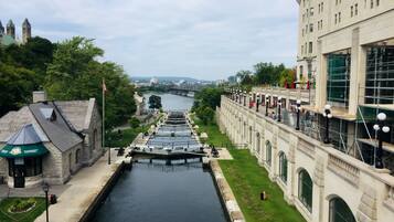 A canal with a lock system, flanked by historic buildings with arched windows and a bridge in the background.
