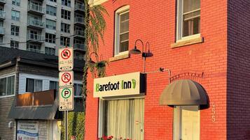 A red brick building with a sign for Barefoot Inn, a no parking sign, and a no smoking sign.