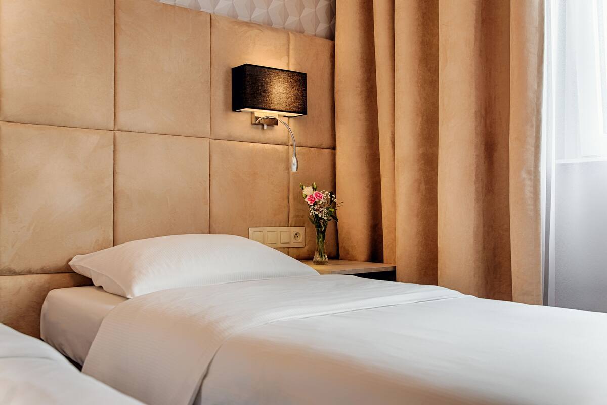 Une chambre d’hôtel avec un grand lit, une table de chevet avec une lampe et un vase rempli de fleurs.
