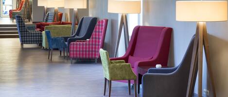 Un hall de hotel con una fila de sillones coloridos y lámparas de pie.