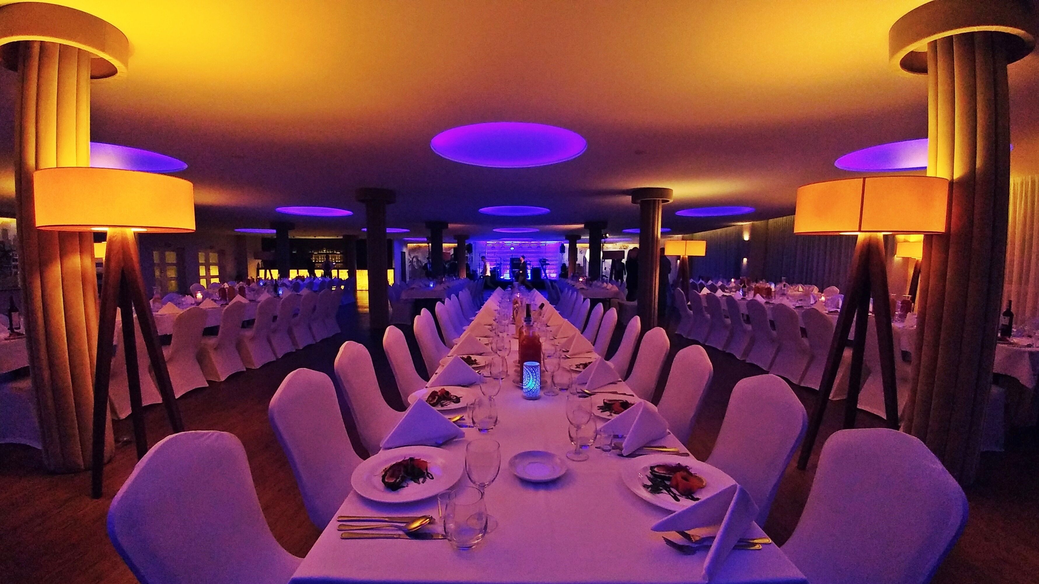 A long banquet table with white tablecloths and chairs, set for a formal event.