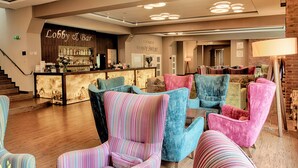 A lobby with striped armchairs, a bar area, and a staircase.
