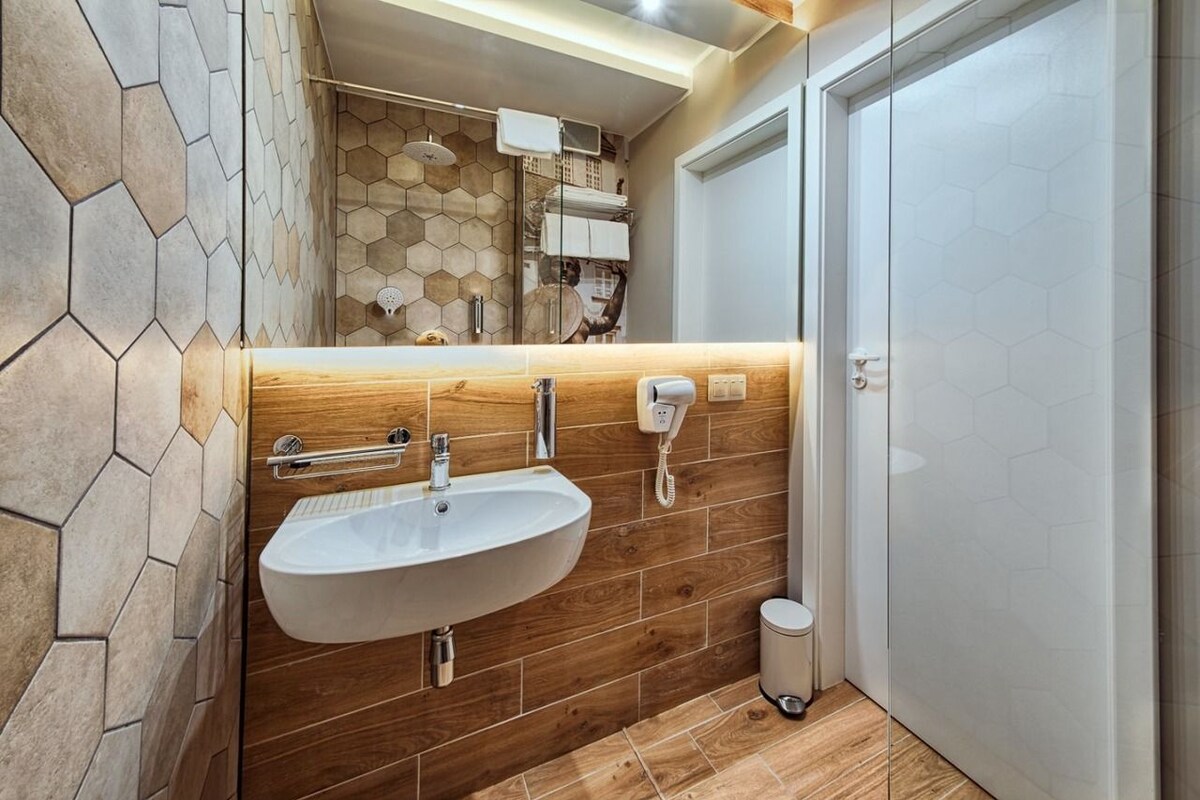 A modern bathroom with a wooden vanity, a white sink, and a mirror.