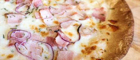 Pizza med skinke og løg på et træbræt.