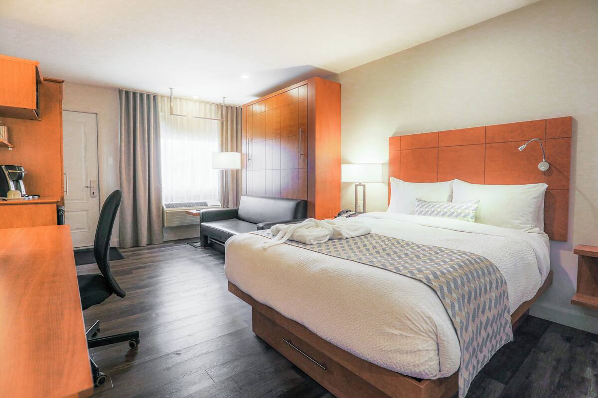 A hotel room with a bed, a desk, a chair, and a wardrobe.