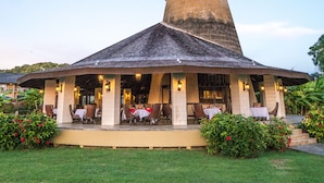 A building with a conical roof and a covered patio area with tables and chairs.