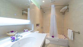 A modern bathroom with a white sink, toilet, and bathtub. There are shelves with towels and a shower curtain.