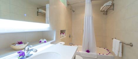 A modern bathroom with a white sink, toilet, and bathtub. There are shelves with towels and a shower curtain.
