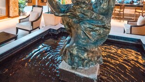 A statue in a pool with a wooden ceiling and a view of the kitchen in the background.