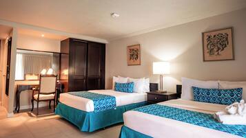 A hotel room with two beds, a desk, and a chair.