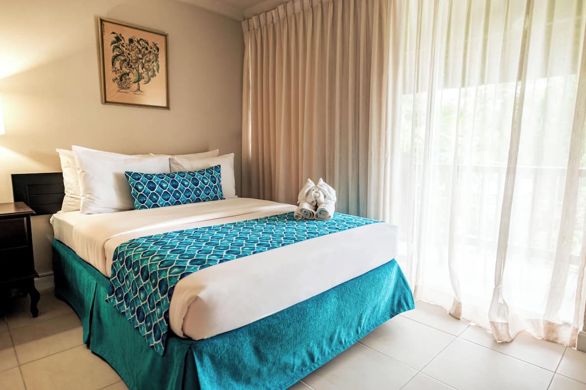 A neatly made bed with a patterned bedspread, a headboard, and a decorative pillow.