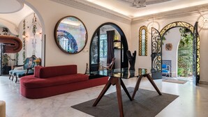 Een ruime woonruimte met een rode bank, een glazen salontafel en decoratieve spiegels.