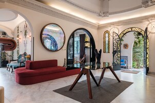 Amplia sala de estar con un sofá rojo, una mesa de centro de vidrio y espejos decorativos.