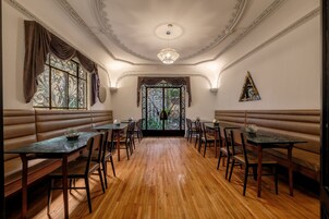 Un comedor con suelo de madera, asientos tapizados tipo cabina y mesas con sillas.