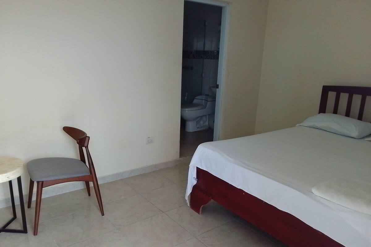 A room with a bed, a chair, and a small table.