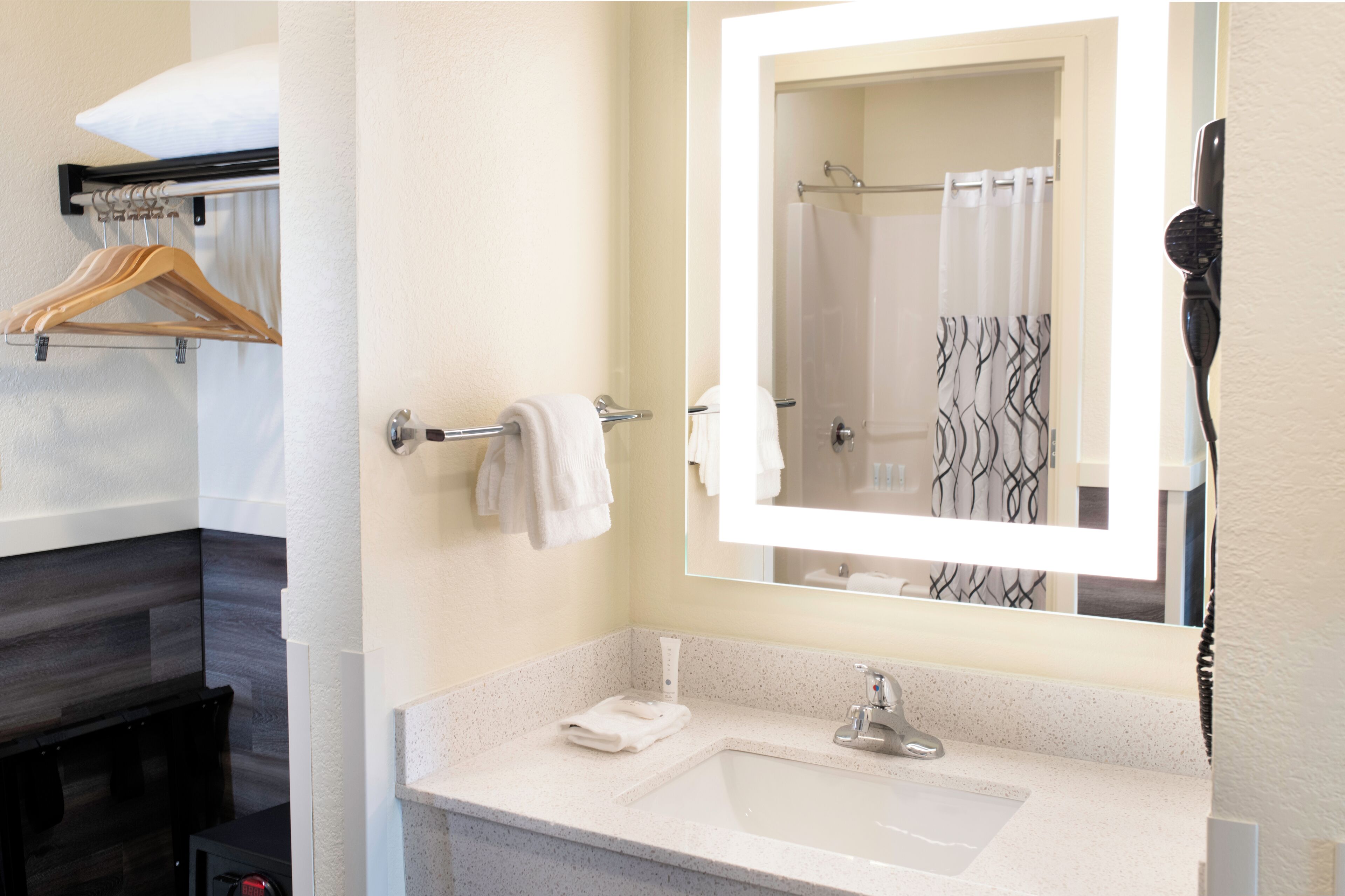 A bathroom with a sink, mirror, towel rack, and a shower curtain.