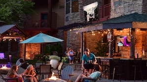 Un espace extérieur aménagé avec des foyers, des chaises et un bar dont la façade est en pierre.