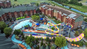 Un resort con un amplio área de piscina, toboganes acuáticos y varias edificaciones con balcones.