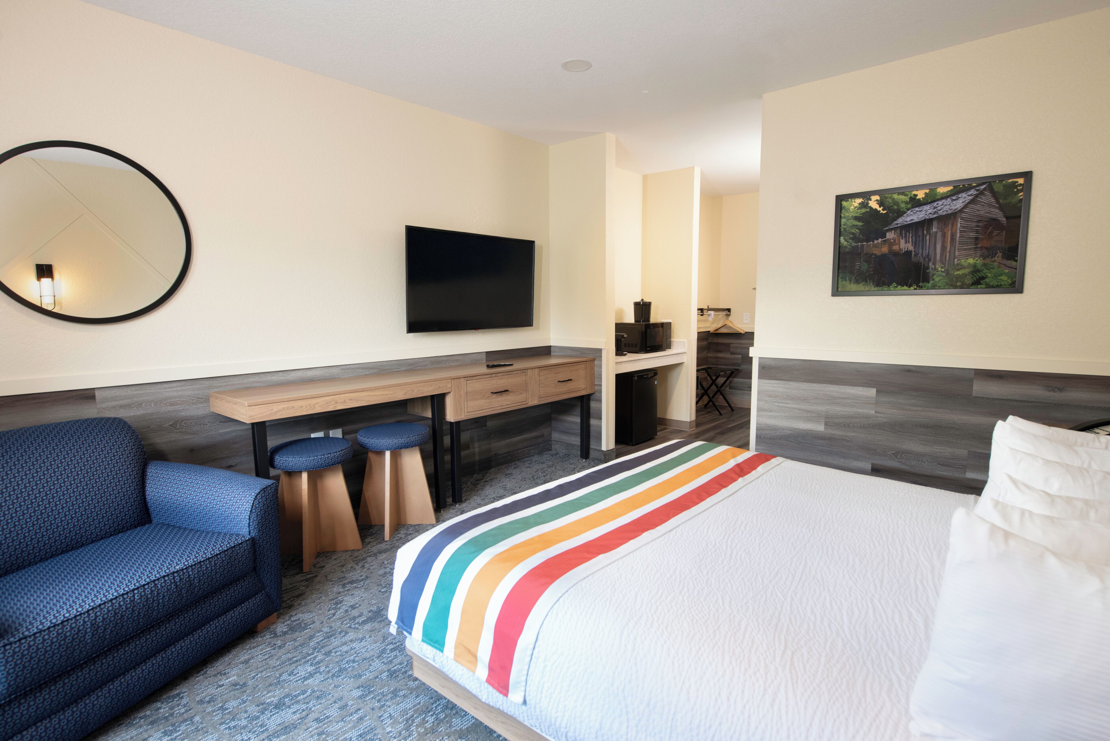 Een moderne hotelkamer met een bed, bureau, stoel en televisie.