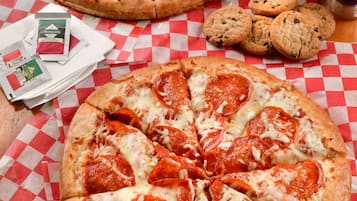 Deux pizzas sur une nappe à carreaux, une bouteille de Pepsi et quelques biscuits.