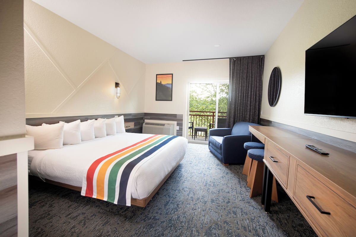 Une chambre d’hôtel avec un grand lit, un bureau, une chaise, une télévision et un balcon avec vue.