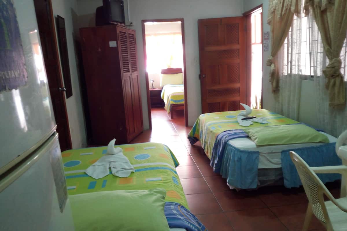 Une chambre avec deux lits, une armoire et un téléviseur.
