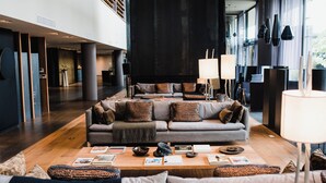 A spacious living area with a large sofa set, a coffee table with magazines and a bowl, and a modern lamp. - Kos Pilar Hotel (Villa Rosa)