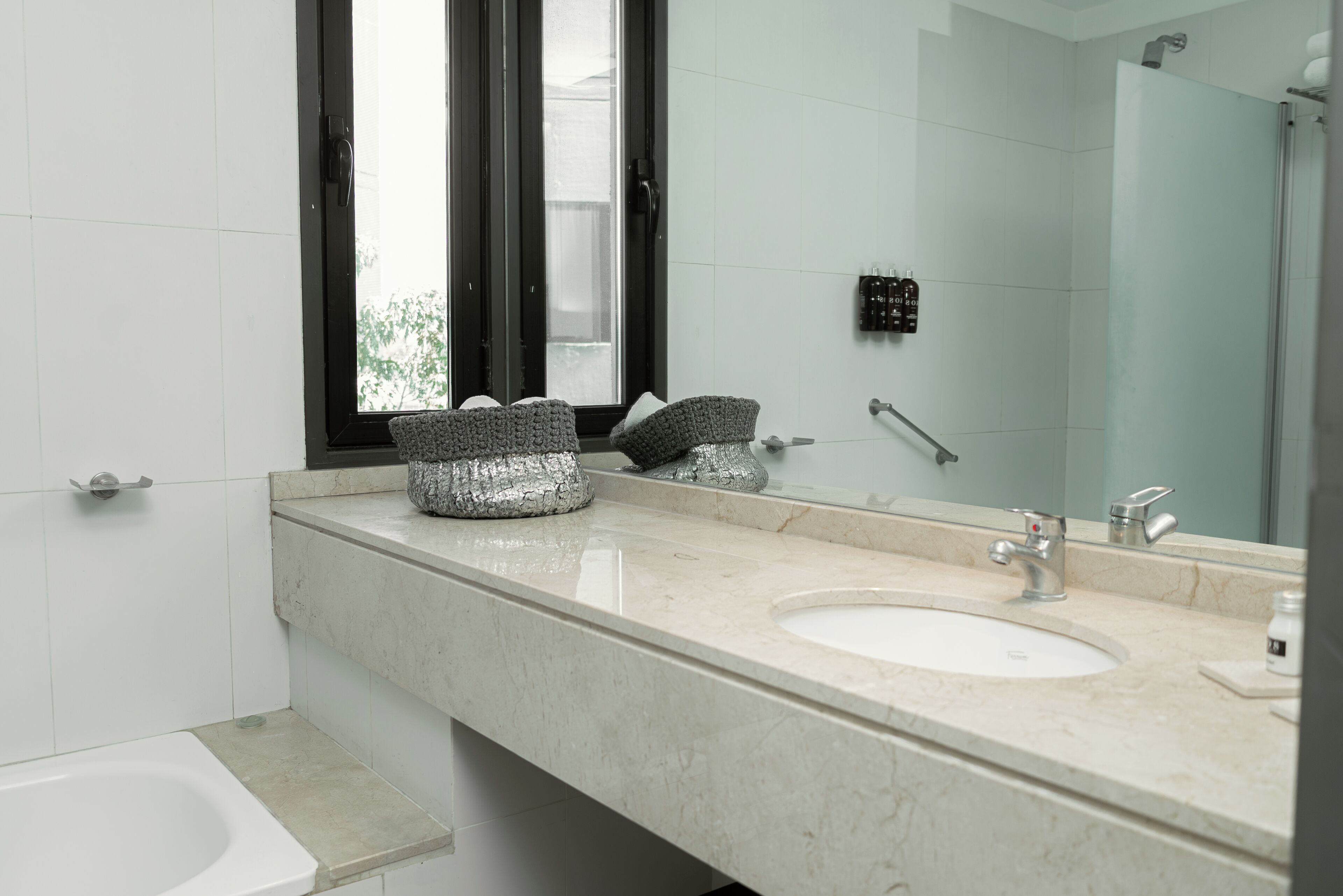 A modern bathroom with a large mirror, a sink, and a shower.