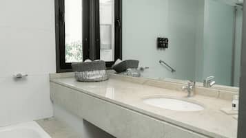 Une salle de bain moderne avec un grand miroir, un lavabo et une douche.