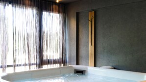 A hot tub with a wooden interior, a wooden bench, and a view of a window with curtains. - Kos Pilar Hotel (Villa Rosa)