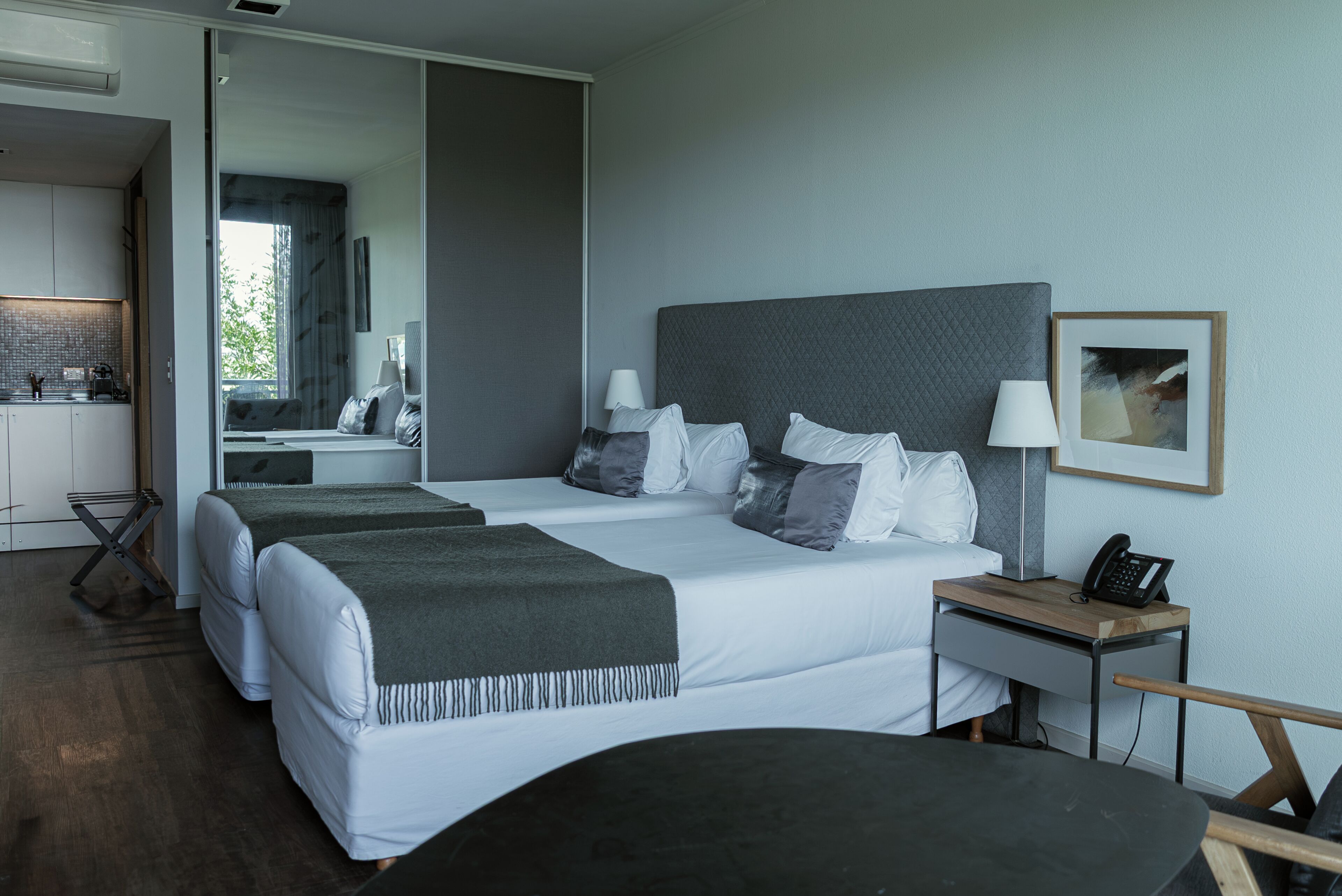 Una habitación de hotel moderna con una cama grande, mesitas de noche, un escritorio y vistas al exterior.