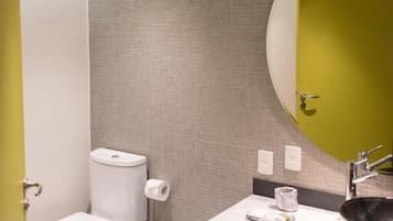 A modern bathroom with a toilet, bidet, sink, and mirror.