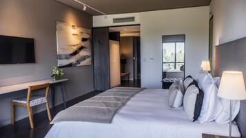 Una habitación de hotel moderna con una cama grande, un escritorio con silla, un televisor de pantalla plana y un cuadro abstracto de gran tamaño en la pared.