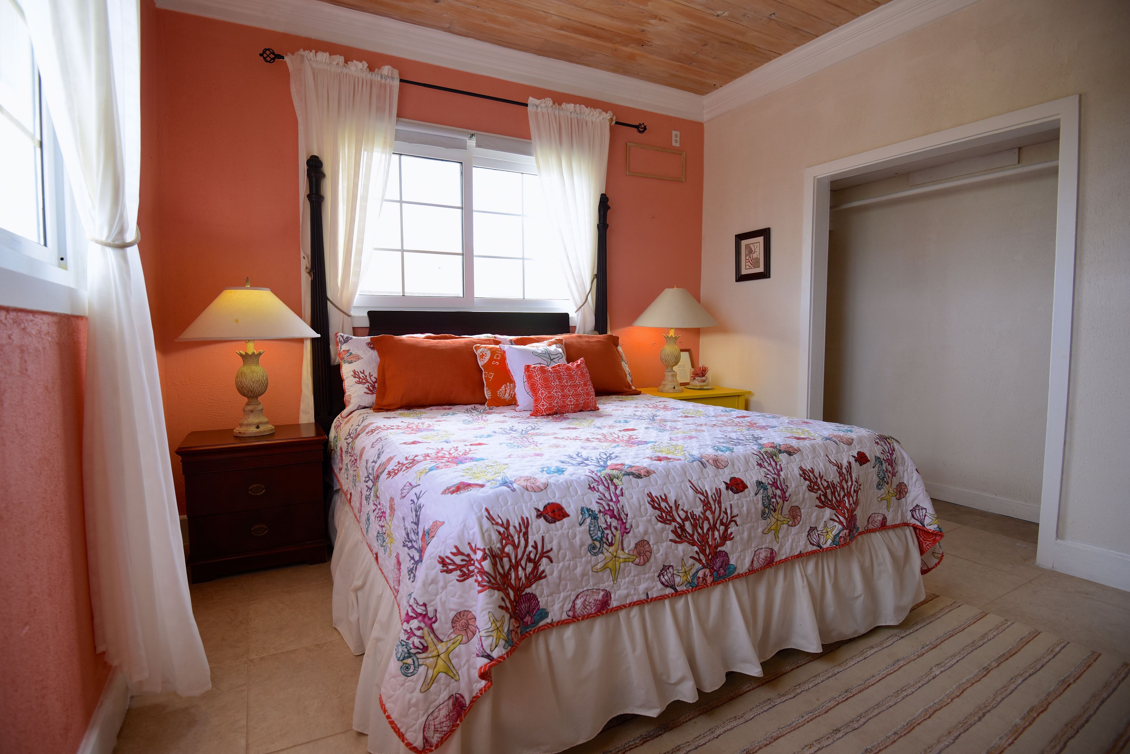 A bedroom with a bed, two bedside tables, a window with curtains, and a door.