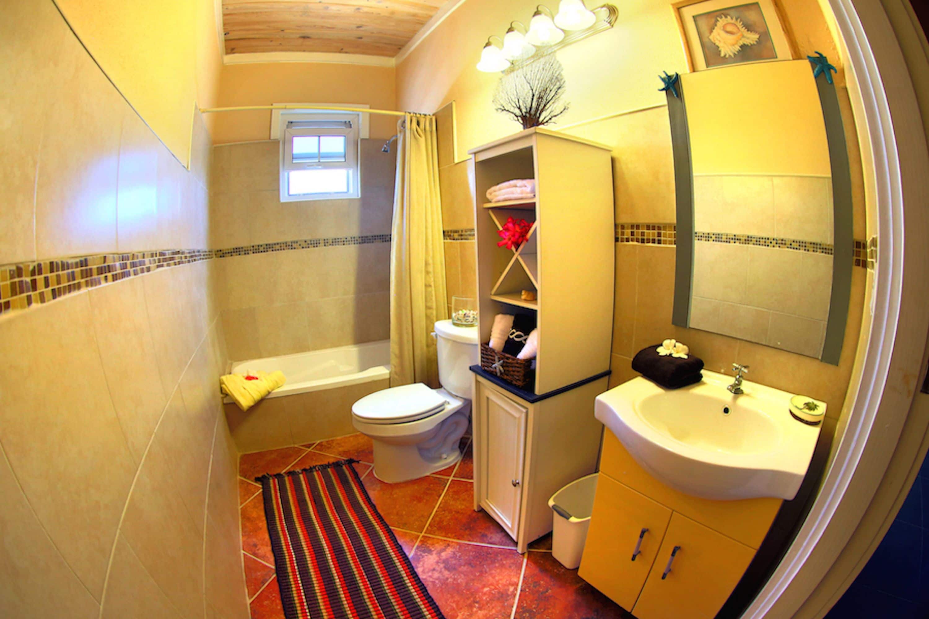 A compact bathroom with a bathtub, toilet, sink, and a small window.