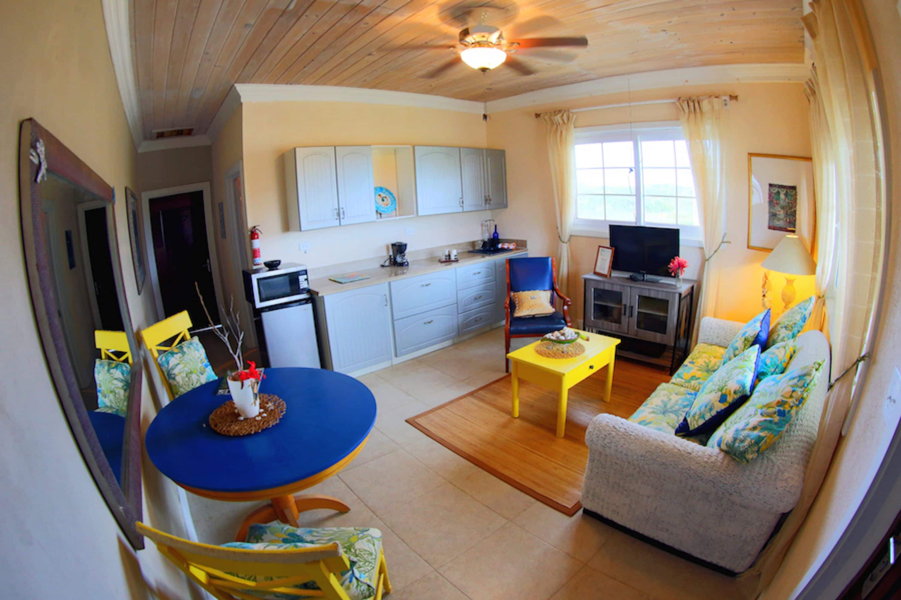 Un espacio habitable compacto con comedor, sofá, televisión y cocina.