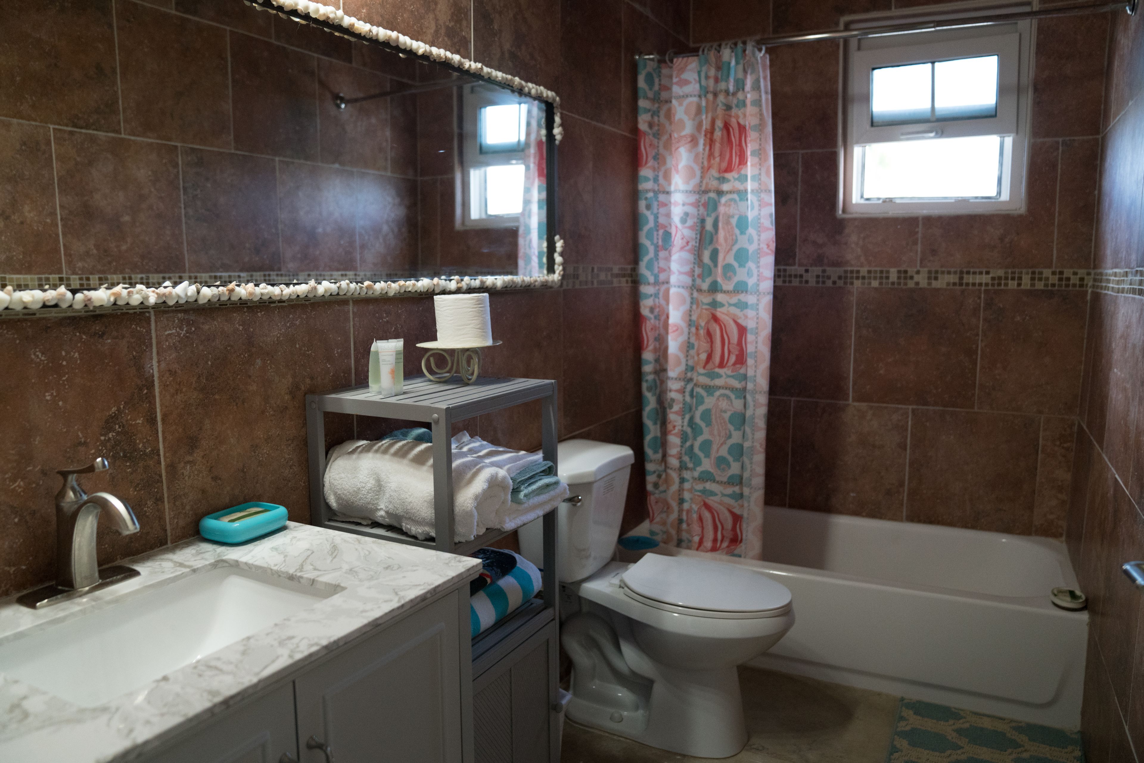 Une salle de bain équipée d’un lavabo, d’un miroir, de toilettes et d’une baignoire.
