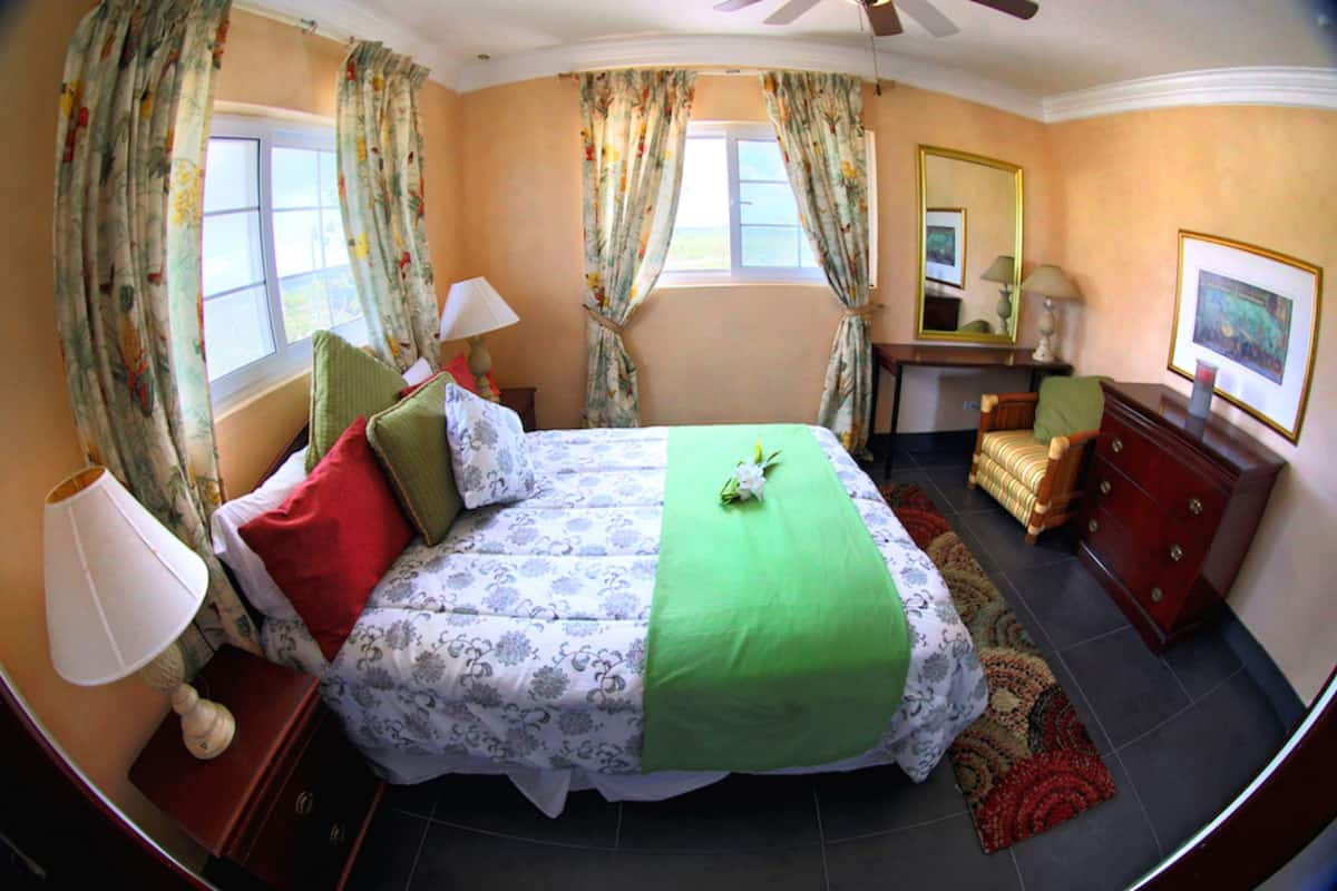 A bedroom with a bed, nightstand, dresser, and a window with curtains.