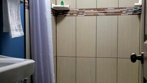 Un pequeño box de ducha con un inodoro y un lavamanos blancos.