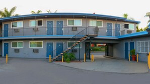 Un edificio de varios pisos con fachada curva, varios balcones y un área de estacionamiento al frente.