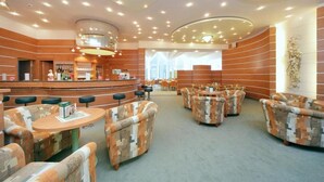 A hotel lobby with a curved reception desk, multiple seating areas with patterned sofas, and a large window providing natural light. - Interhotel Montana (Spindleruv Mlyn)