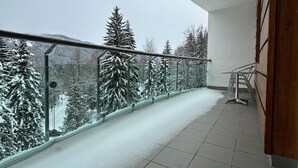 A balcony with a metal railing, tiled floor, and a view of snow-covered trees. - Interhotel Montana (Spindleruv Mlyn)