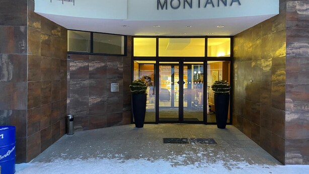 The entrance of a hotel named 'MONTANA' with a modern design, featuring a glass door entrance and two potted plants. - Interhotel Montana (Spindleruv Mlyn)