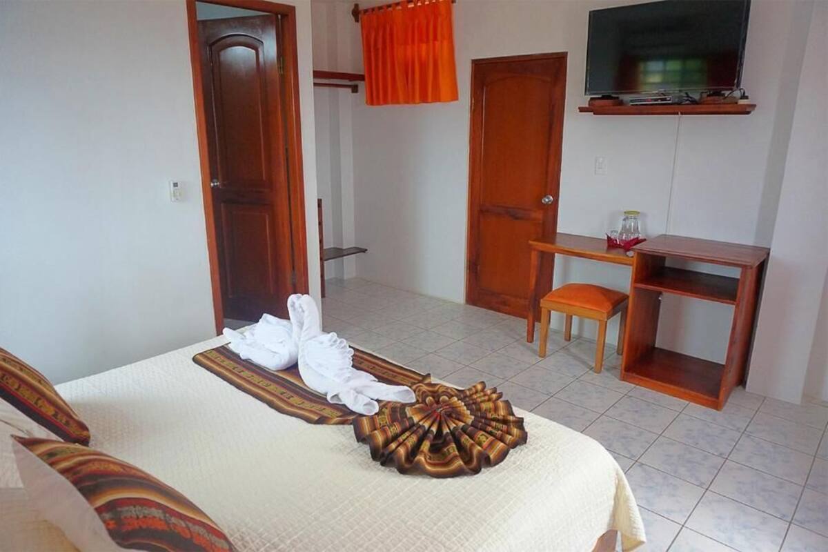 Ein Hotelzimmer mit Bett, Schreibtisch, Stuhl, Fernseher und einer Badezimmertür.
