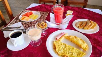 A breakfast table with a variety of food items including eggs, toast, fruit, and a glass of juice.