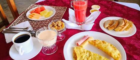 Una mesa de desayuno con diversos alimentos como huevos, tostadas, fruta y un vaso de jugo.